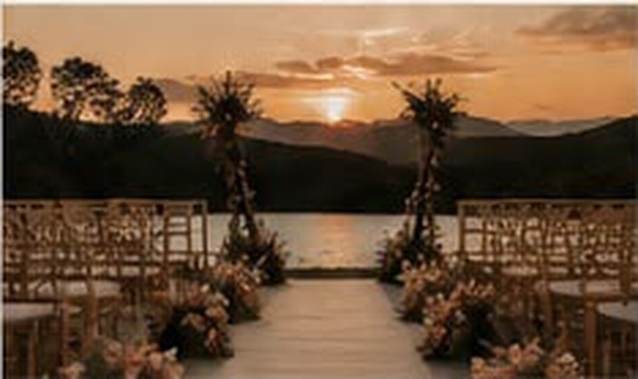 Altar de casamento ao ar livre montado à beira do lago no pôr do sol.
